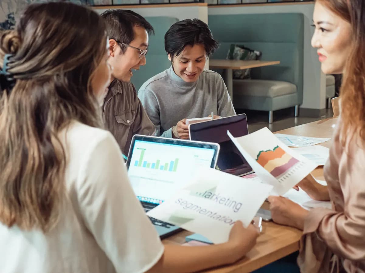 Colleagues discussing marketing charts and reports around a table
